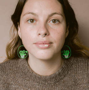Woman wearing the DENZ Midi Pilea plant earrings in Bright Green/Pink 