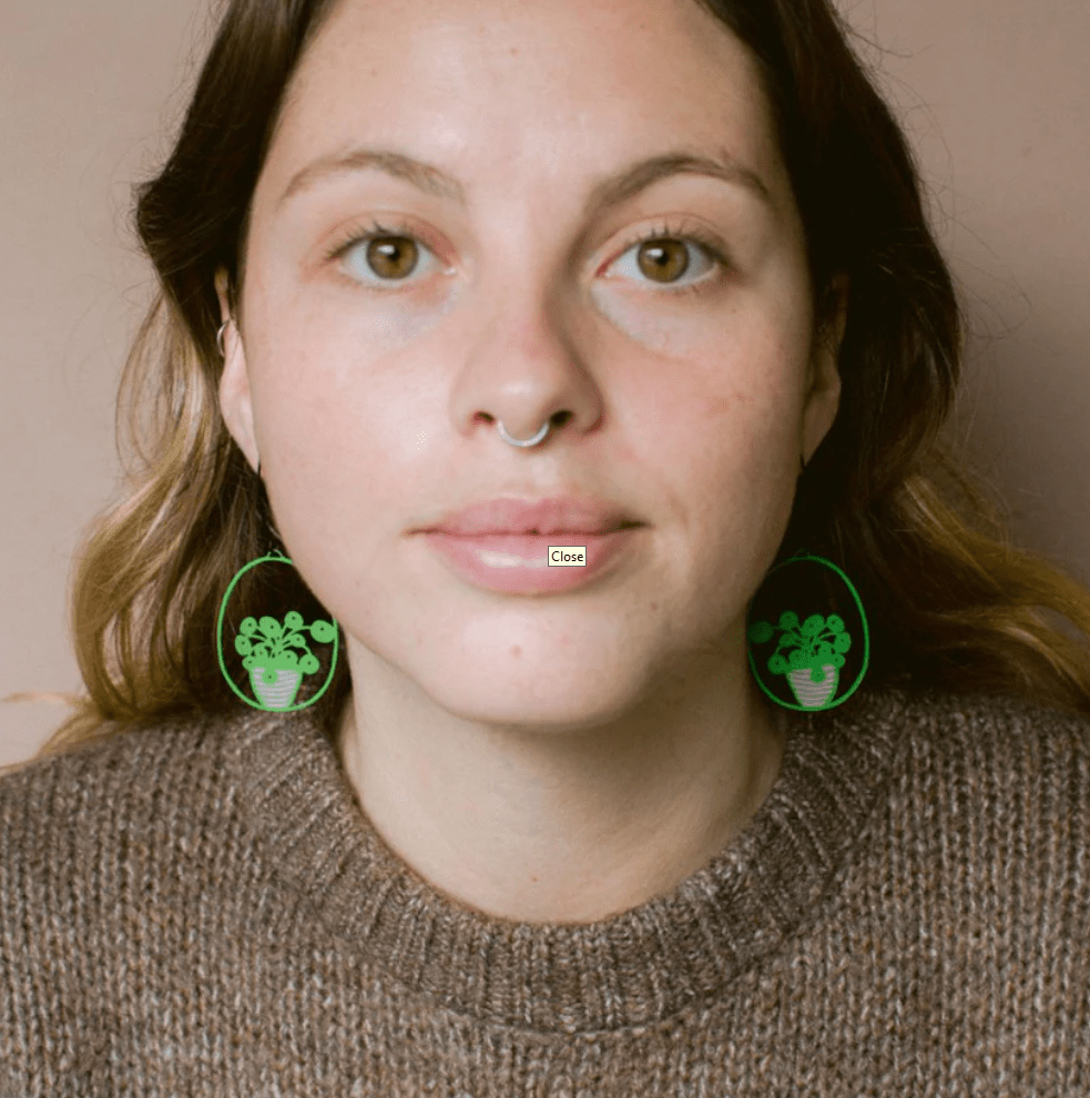 Woman wearing the DENZ Midi Pilea plant earrings in Bright Green/Pink 