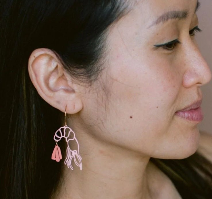 Side profile of a woman wearing Denz Midi Prawn Dangle Earrings in Coral