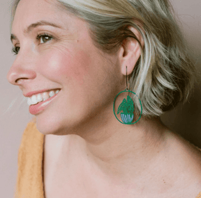 Side profile of a woman wearing DENZ Midi Spotted Begonia plant earrings in Dark Green/Purple 