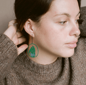 Woman wearing the DENZ Midi Spotted Begonia plant earrings in Dark Green/Purple 
