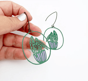 DENZ Midi Spotted Begonia plant earrings in Dark Green/Purple, held by hand