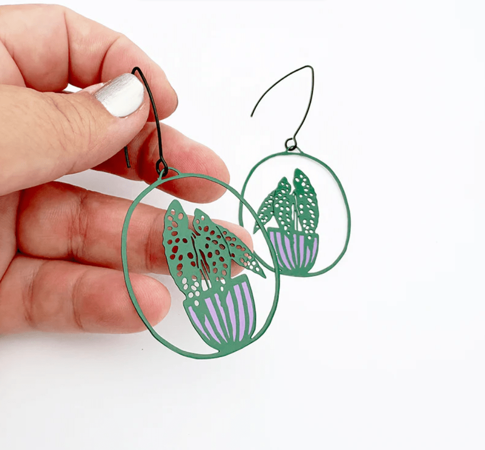 DENZ Midi Spotted Begonia plant earrings in Dark Green/Purple, held by hand