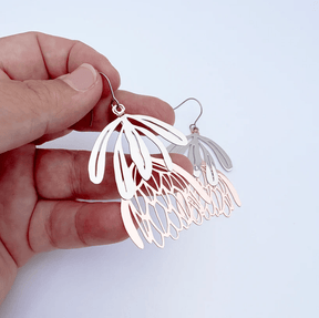 DENZ Protea flower dangle earrings in Silver/Rose Gold, held by hand