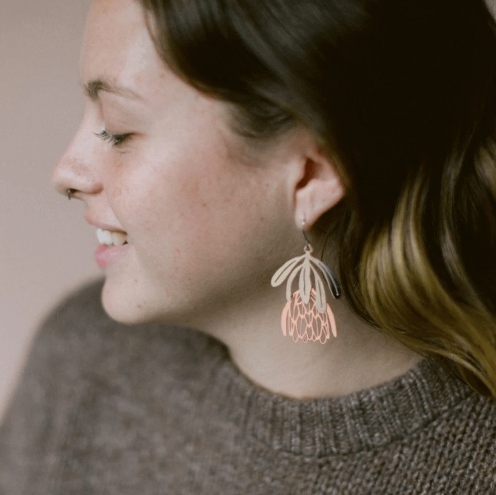 Side profile of woman wearing the DENZ Protea flower dangle earrings in Silver/Rose Gold 