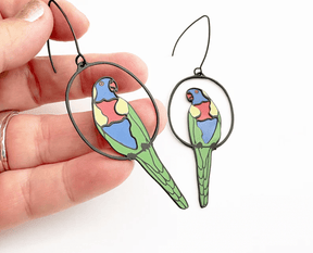 DENZ Rainbow Lorikeet earrings in Black/Rainbow, held by hand
