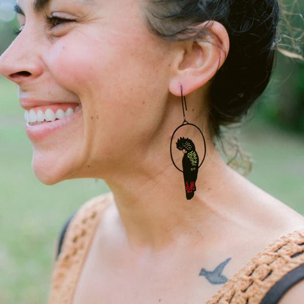 SIde profile of woman wearing Denz Red Tailed Black Cockatoo Earrings in Black/Red/Yellow 
