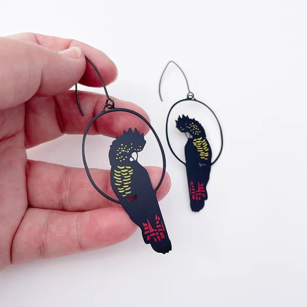 Denz Red Tailed Black Cockatoo Earrings in Black/Red/Yellow, held by hand