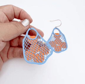 DENZ String Bag earrings (with fruits) in Blue with Oranges, held by hand