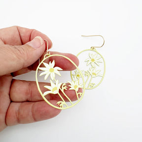 A hand holding a pair of Flannel Flower earrings in Lemon & Cream against a plain white background.