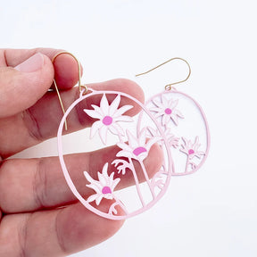 Hand holding a DENZ Flannel Flower earrings against a white background