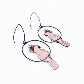 A pair of DENZ Pink Cockatoo earrings inside black circular frames, suspended from thin black wires on a plain white background.