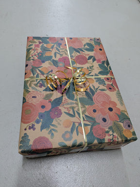 Gift box with floral pattern and gold ribbon on a gray surface from Pookipoiga.