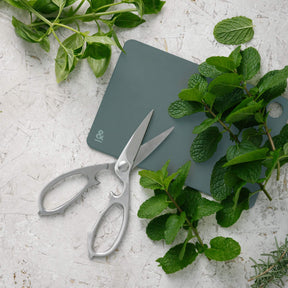 Seed & Sprout Mini Chopping Board in eucalyptus and Kitchen Shears with Fresh Herbs Flat Lay.