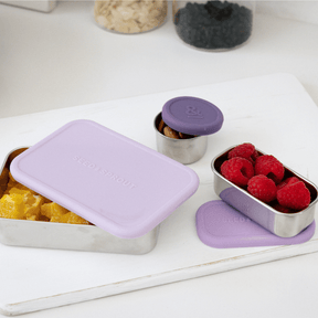 Seed & Sprout stainless steel containers and leakproof silicone pots in plum tones, filled with fresh fruit and snacks.