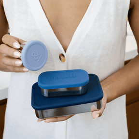 Seed & Sprout stainless steel containers and leakproof snack pots in indigo, h tones held by a person in a white top. 
