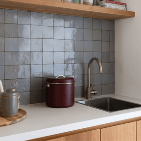Seed & Sprout mulberry kitchen compost bin placed neatly on a white countertop next to a stainless steel sink and stylish tiled backsplash.