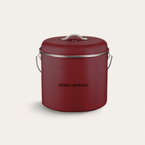 Seed & Sprout kitchen compost bin in mulberry red featuring a vented lid, side handle, and branded typography.