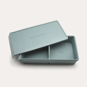 An open Seed & Sprout 2 Portion Silicone Freezer Tray with two partitioned sections and its matching embossed lid resting partially on top.