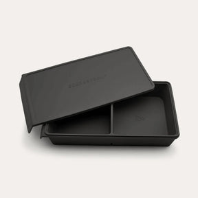 An open Seed & Sprout 2 Portion Silicone Freezer Tray in Liquorice with two partitioned sections and its matching embossed lid resting partially on top.