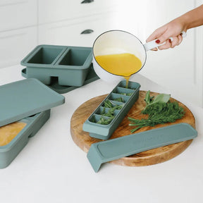 Seed & Sprout silicone freezer tray being filled with broth and herbs for meal prep.