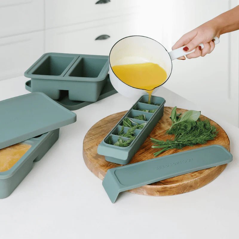 Seed & Sprout silicone freezer tray being filled with broth and herbs for meal prep.