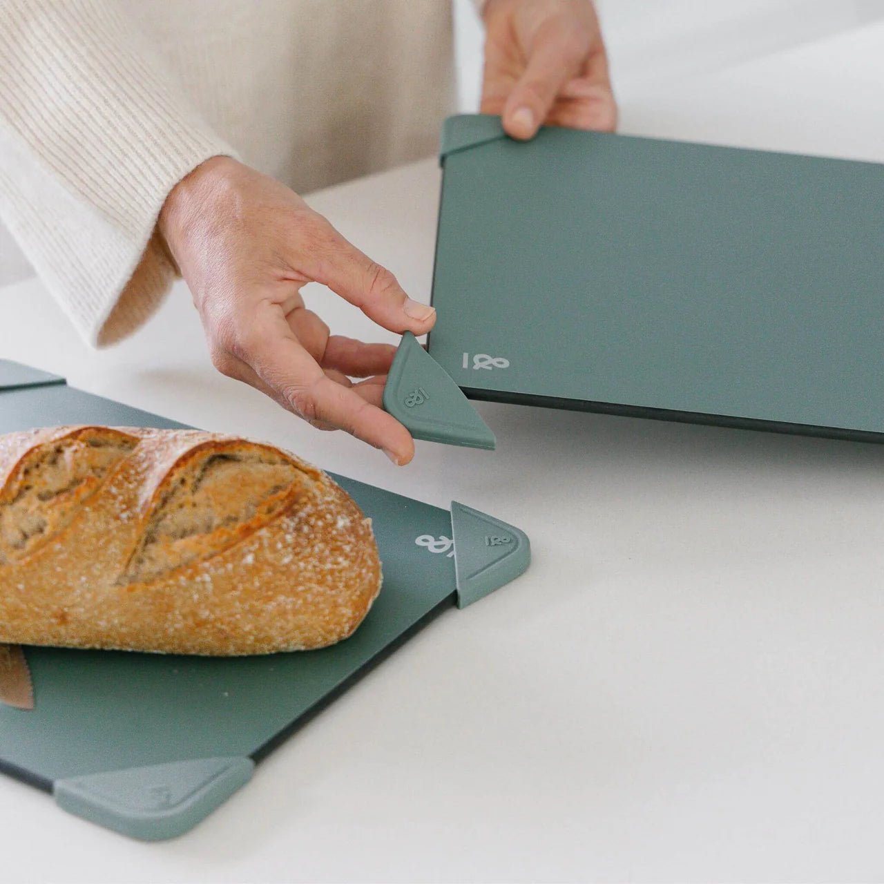 Seed & Sprout Anti-Slip Chopping Board Corners in eucalyptus being placed on a cutting board.