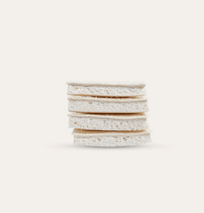 Seed & Sprout compostable cellulose and loofah sponges neatly stacked in a horizontal pile.