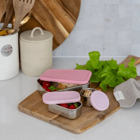 Seed & Sprout CrunchBox™ OG Snack Pots and Split Snackpot with plum and peony silicone lids styled on a cutting board.