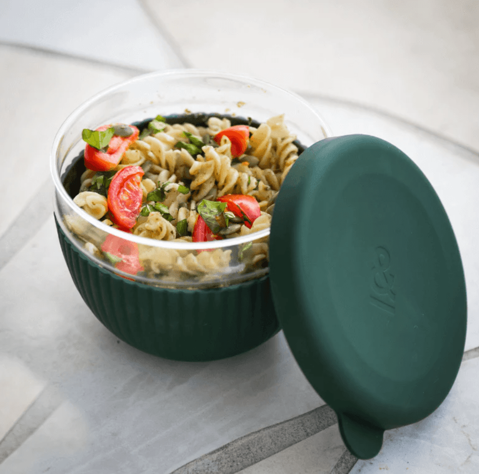 Seed & Sprout 1000ml glass lunch bowl in Moss filled with pesto pasta salad, featuring a ribbed silicone protective base and a matching leakproof silicone lid resting beside it.   