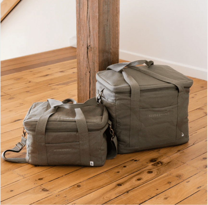 Seed & Sprout insulated cooler bags in olive placed on a wooden floor next to a timber pillar, showcasing the 15L and 28L sizes.