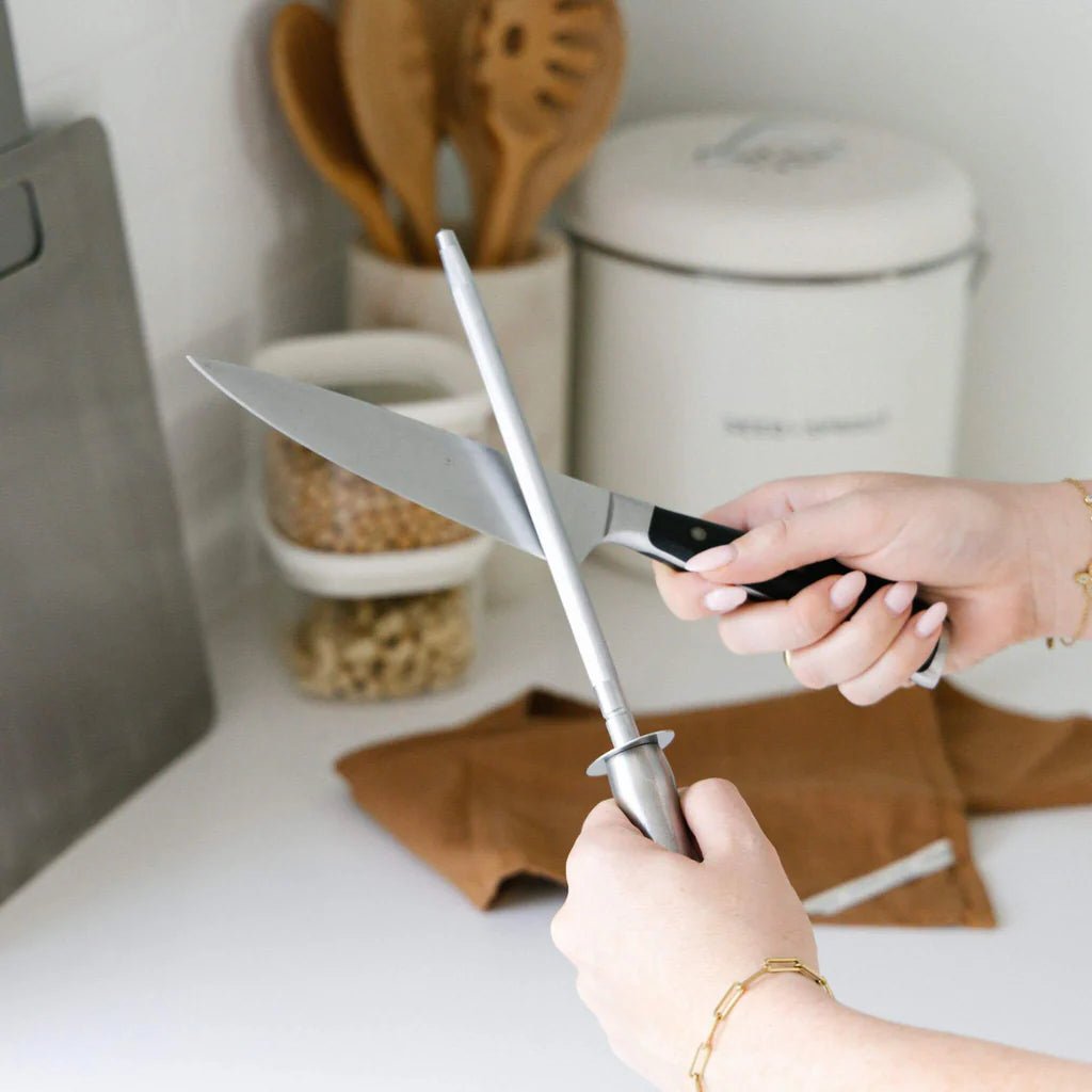 A person sharpening a kitchen knife against a Seed & Sprout Knife Sharpener in a kitchen setting.