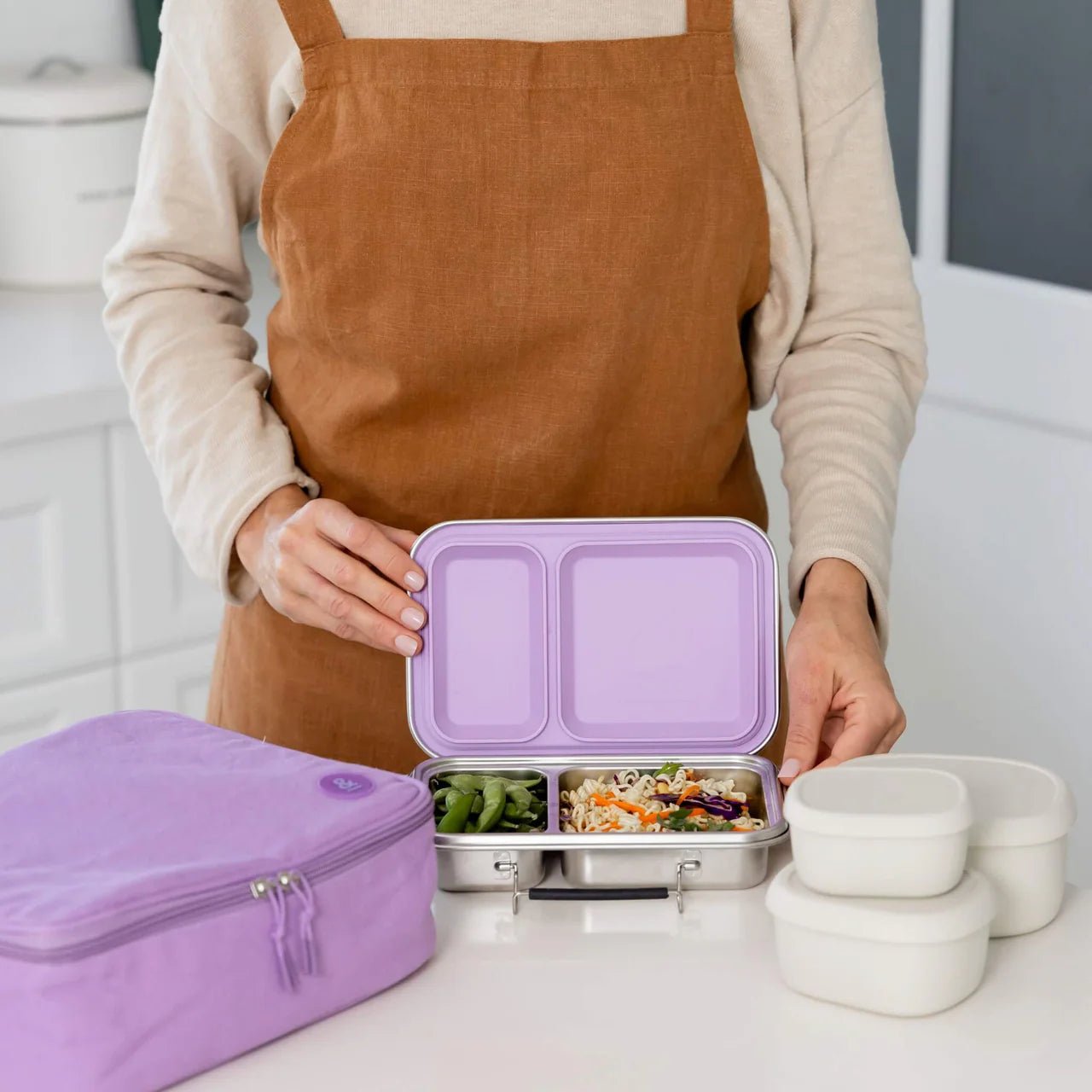 Seed & Sprout meal prep setup featuring a stainless steel lunch box, lilac lunch bag, and silicone nesting containers.