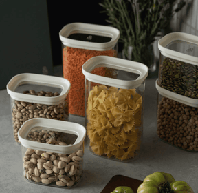 Seed & Sprout Tallow glass pantry containers with oatmeal-colored lids, neatly arranged on a countertop and filled with various dry foods.