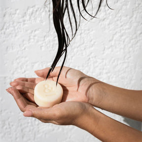 Seed & Sprout solid conditioner bar held in wet hands during a hair wash routine.