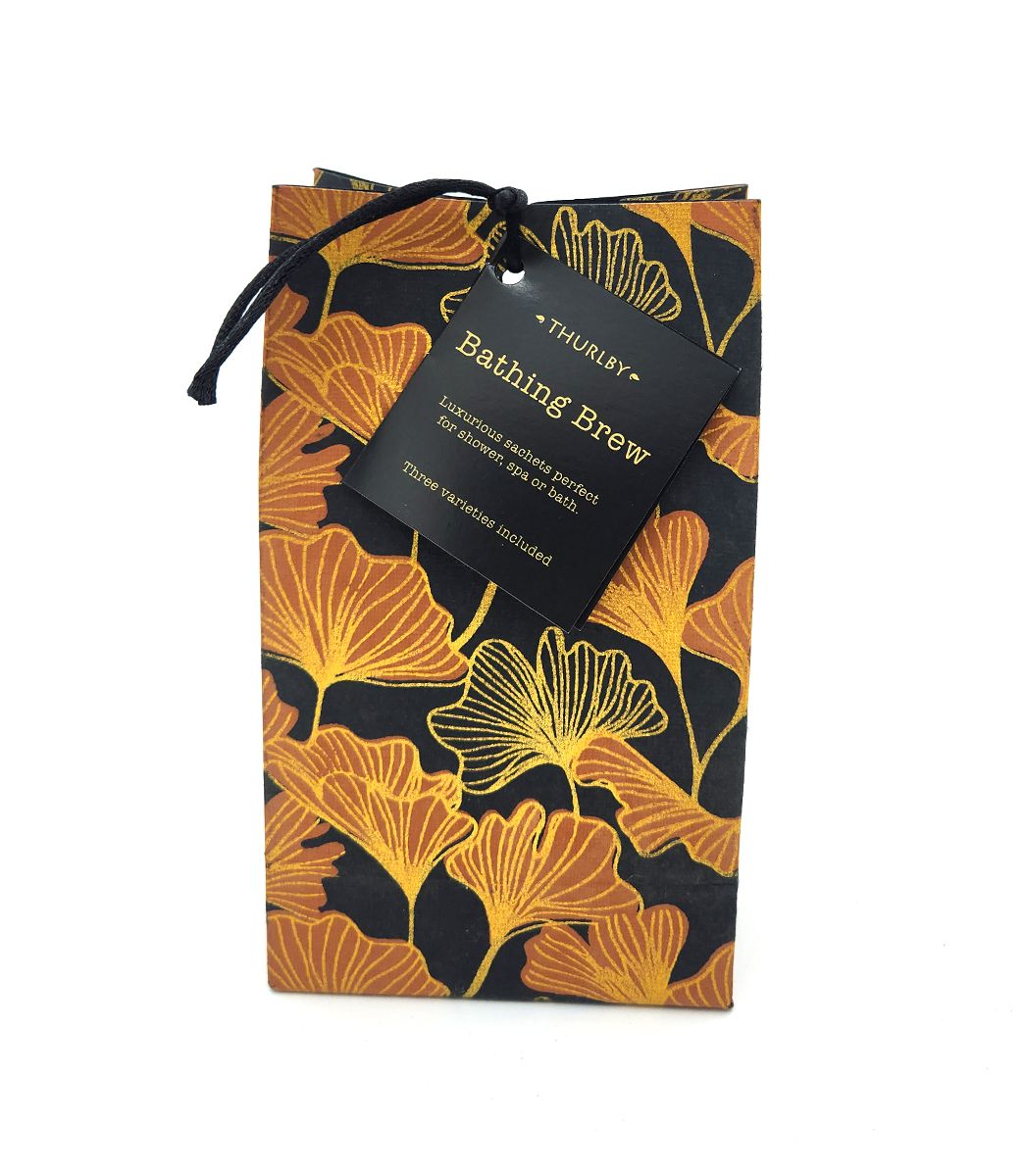 Thurlby Herb Farm Gingko Bathing Brew packaging featuring a black paper bag with an orange and gold ginkgo leaf pattern, tied with a black cord and a branded tag.