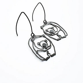 A pair of dark metallic cutout DENZ Wombat, shown on a plain white background.