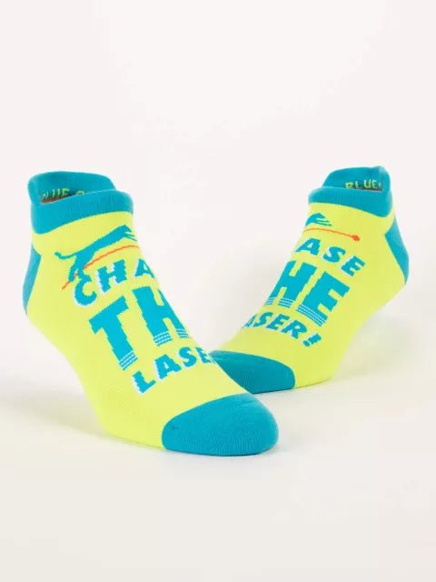 A pair of bright yellow and teal Blue Q ankle sneaker socks featuring a pouncing cat silhouette and the text "CHASE THE LASER!".