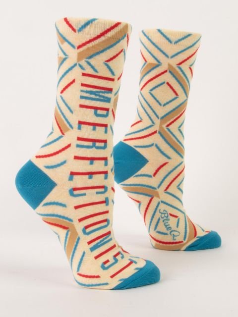 A pair of cream Blue Q women's crew socks featuring turquoise heels and toes, geometric line patterns, and vertical text reading "IMPERFECTIONIST."