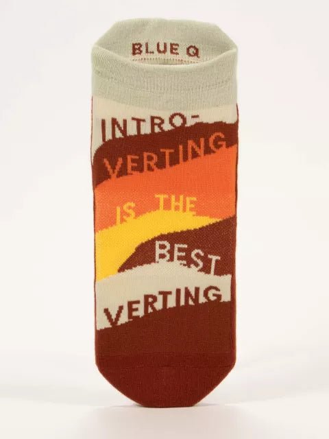 A pair of colorful Blue Q socks with text 'INTROVERTING IS THE BEST VERTING' on the ankle area, predominantly in red and orange tones.