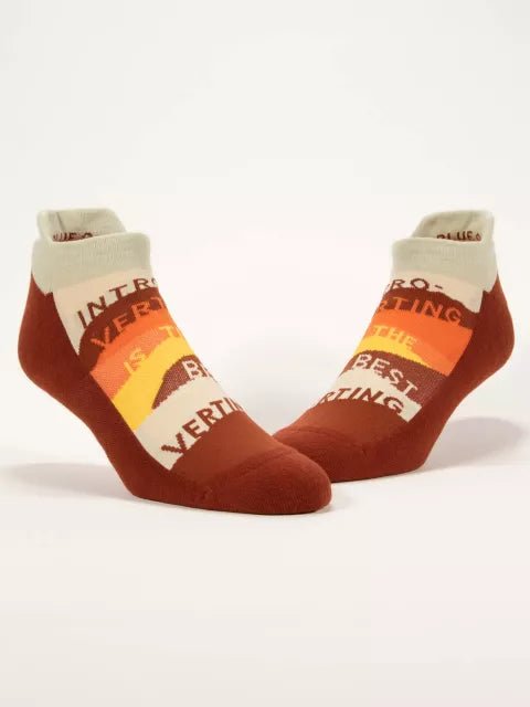 A pair of Blue Q ankle-length sneaker socks featuring a retro 70s striped graphic with the text "Introverting Is The Best Verting".