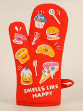 A Blue Q oven mitt decorated with cheerful smiley-faced food items and white text reading "SMELLS LIKE HAPPY" near the cuff.