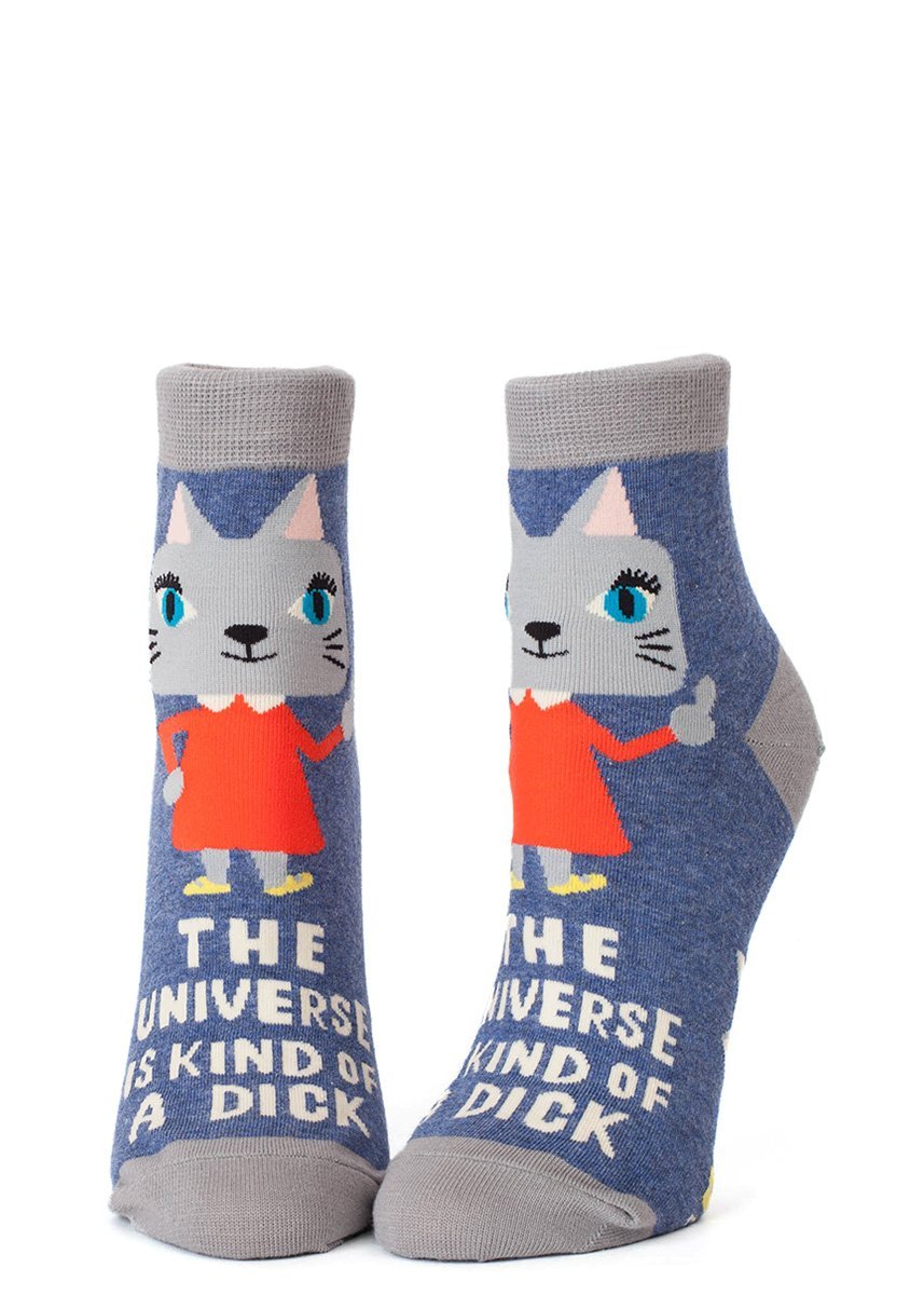 Front-facing studio view of a pair of Blue Q women's denim blue ankle socks featuring a cat giving a thumbs-up and white text reading "THE UNIVERSE IS KIND OF A DICK".