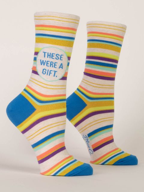 A pair of cream Blue Q women's crew socks with vibrant multicolored stripes and a circle badge reading "THESE WERE A GIFT."