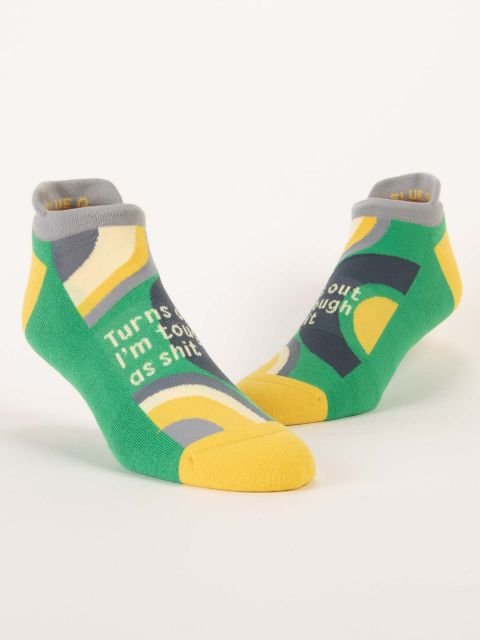 Pair of Blue Q low-cut sneaker socks in green, yellow, grey, and dark blue reading "Turns out I'm tough as shit".