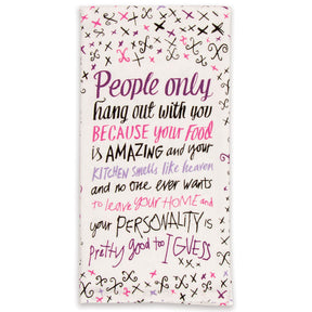 A white folded Blue Q tea towel printed with purple, pink, and black calligraphy stating "People only hang out with you because your food is AMAZING".
