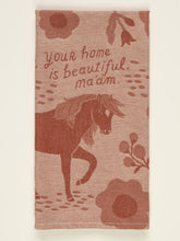 A dusty rose folded Blue Q woven tea towel featuring a horse illustration surrounded by flowers and handwritten text reading "Your home is beautiful, ma'am."