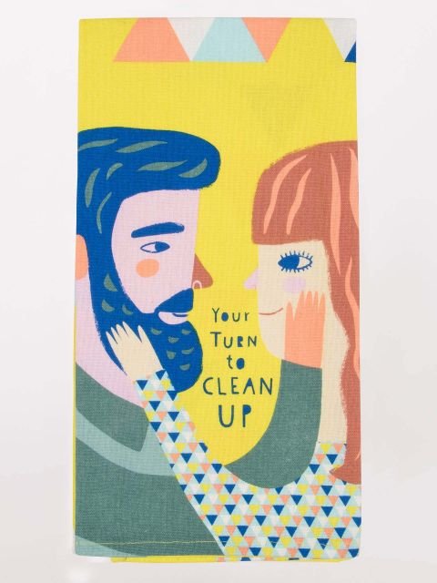 A yellow Blue Q tea towel featuring an illustration of a couple gazing lovingly at each other with handwritten text reading "Your Turn to CLEAN UP."