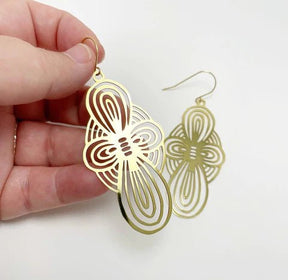 DENZ Bow dangles in gold, held by hand