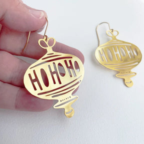 DENZ Ho Ho Ho in Gold earrings, held by hand